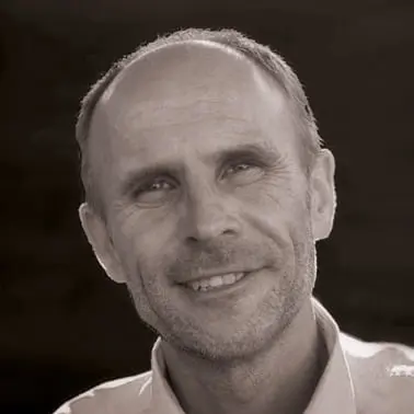 Homme souriant en portrait noir et blanc.